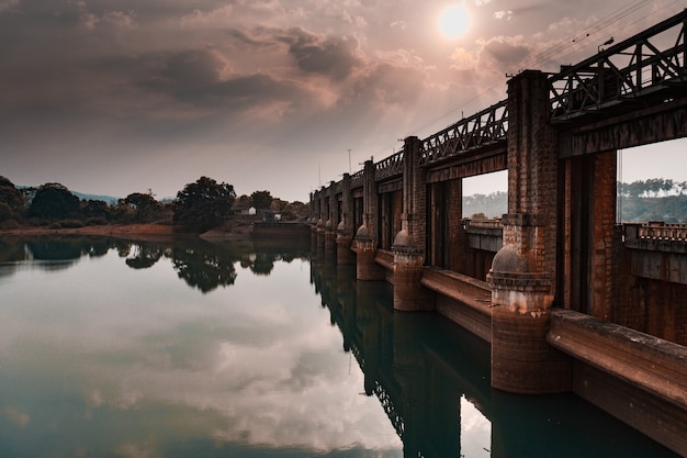 Prachtig uitzicht op een oude stenen brug die bij zonsopgang in het heldere water van de rivier reflecteert