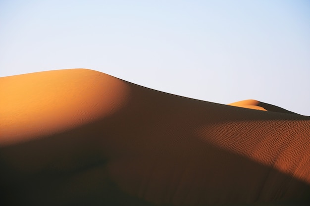 Prachtig uitzicht op een woestijn tijdens zonsondergang onder een lichtblauwe hemel