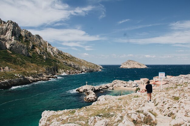 Prachtig uitzicht op enorme rotsen en een rustige zee met een jonge vrouw die ronddwaalt, Marseille, Frankrijk