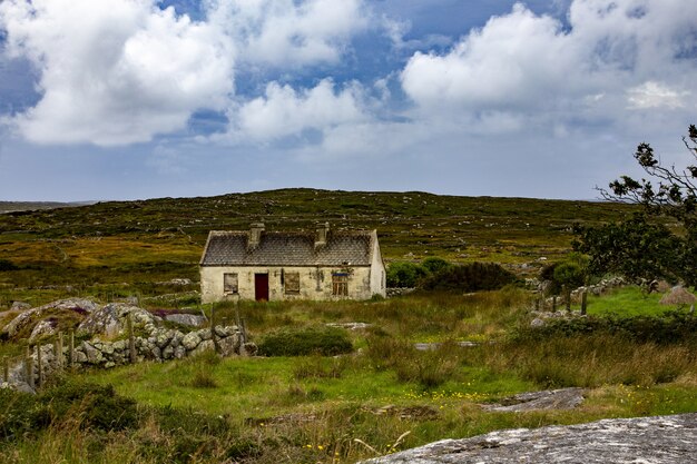 Prachtig uitzicht van een verlaten huisje in County Mayo op een grasveld onder de bewolkte hemel