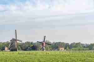 Gratis foto prachtig uitzicht van windmolens op een veld met een bewolkte blauwe lucht op de achtergrond