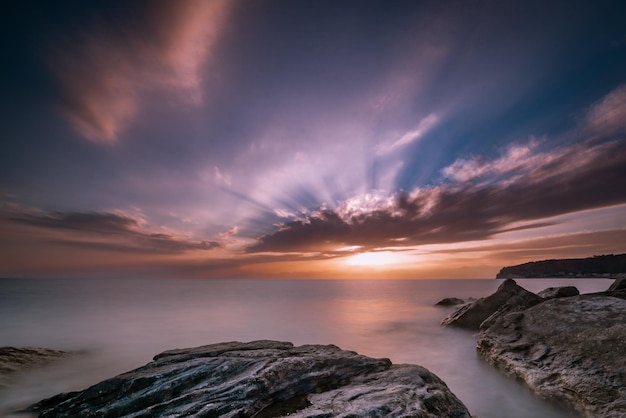 Prachtig zeegezicht bij zonsondergang met rotsformaties in het water