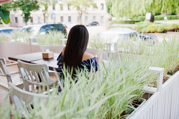 Prachtige brunette meisje zittend op de tafel in café met kopje koffie en drankje