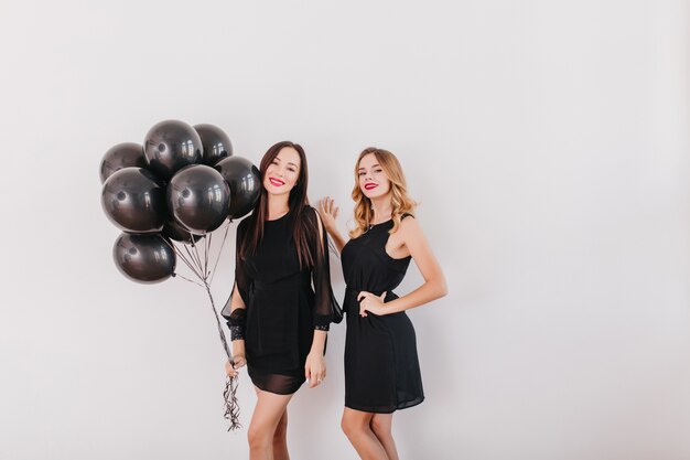 Prachtige brunette vrouwen staan met zwarte ballonnen in de studio