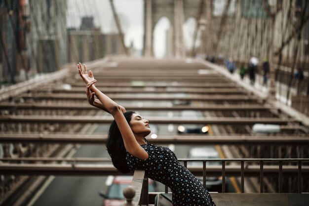 prachtige en tedere Indiase vrouw in zwarte jurk poseren voor de Brooklyn bridge