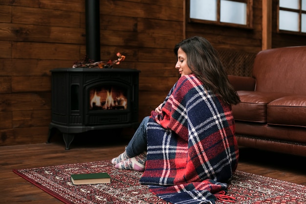 Prachtige jonge vrouw naast de open haard