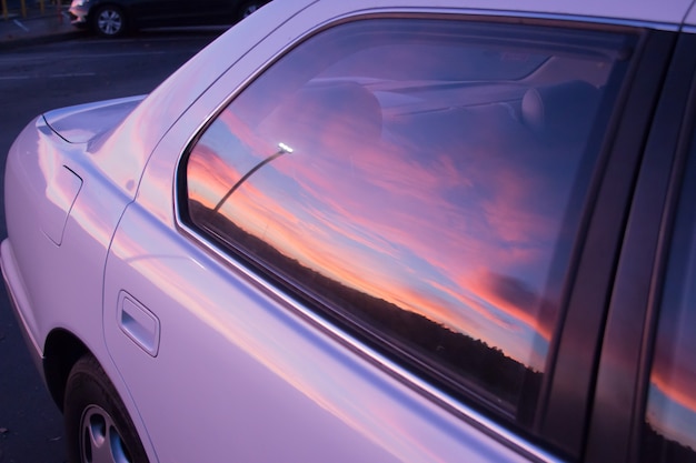 Prachtige kleuren van de avondrood weerspiegeld in het raam van een paarse auto