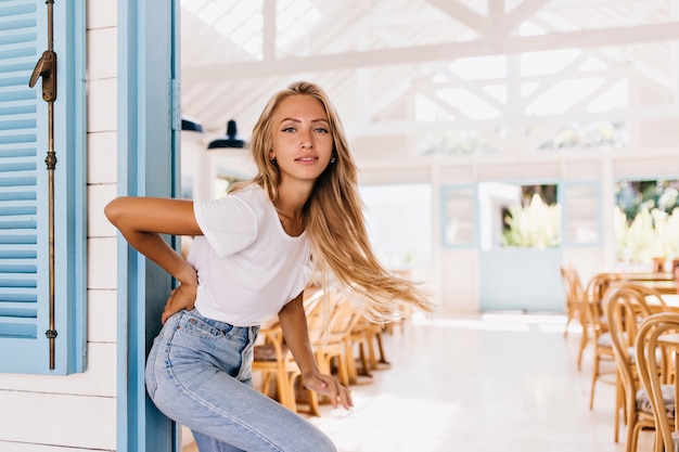 Prachtige licht gebruinde vrouw in retro jeans poseren met een positieve glimlach.