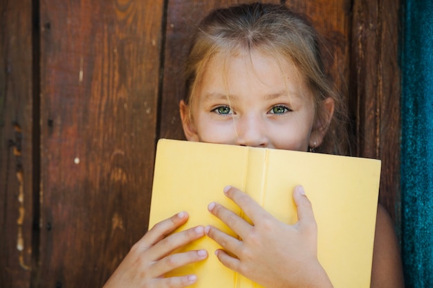 Pretty little girl covering with book