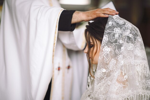 Priester zegent bruid tijdens de ceremonie in de kerk