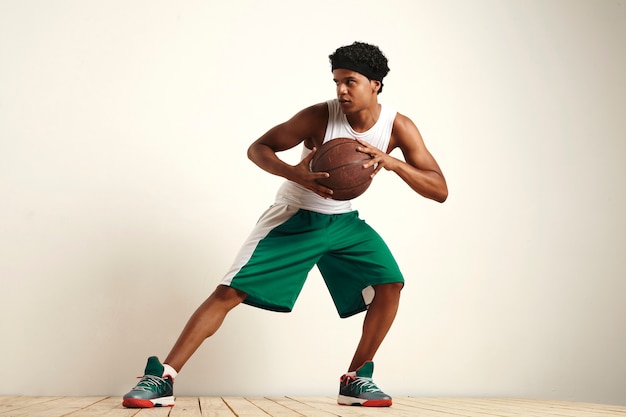 professionele basketbalspeler oefenen verdediging met een oude lederen basketbal geïsoleerd op wit