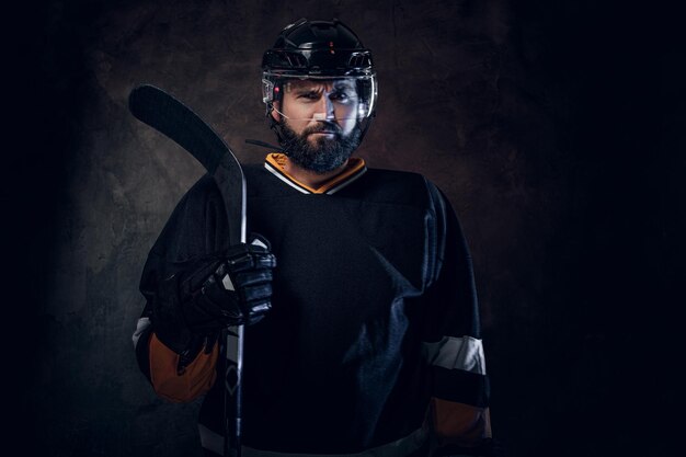 Professionele bebaarde man in hockeyspeler uitrusting poseert voor fotograaf.
