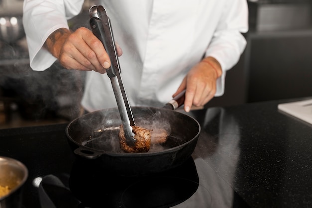 Gratis foto professionele chef-kok die voedsel in de keuken bereidt