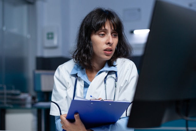 Professionele dokter kijkt naar computerscherm en medische dossiers