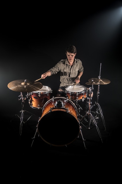 Gratis foto professionele drummer spelen op drumstel op het podium op de zwarte achtergrond met drumstokken en vintage look. bovenaanzicht. rookeffect