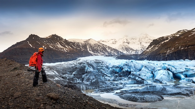 Professionele fotograaf met camera en statief in de winter. professionele fotograaf op zoek naar gletsjer in IJsland.