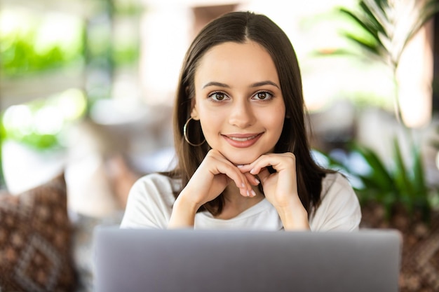 Professionele front-end ontwikkelaar vrouw die de prestaties van de website op een laptop bewaakt terwijl ze op afstand werkt. Internationaal studentenmeisje dat naar een webseminar kijkt terwijl ze in een coffeeshop rust.
