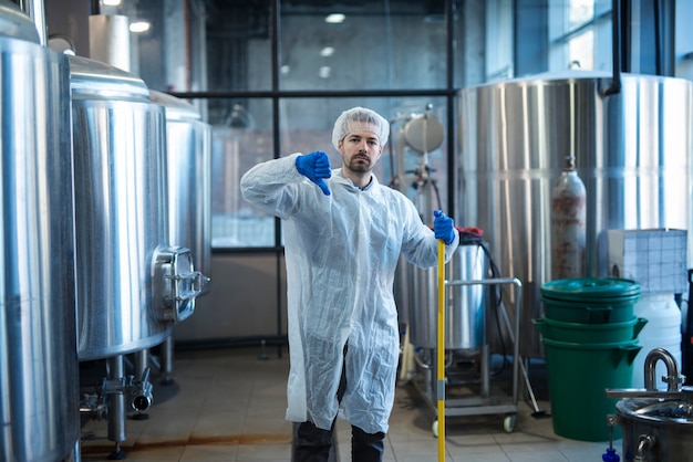 Professionele industriële reiniger in beschermend uniform met de duim naar beneden