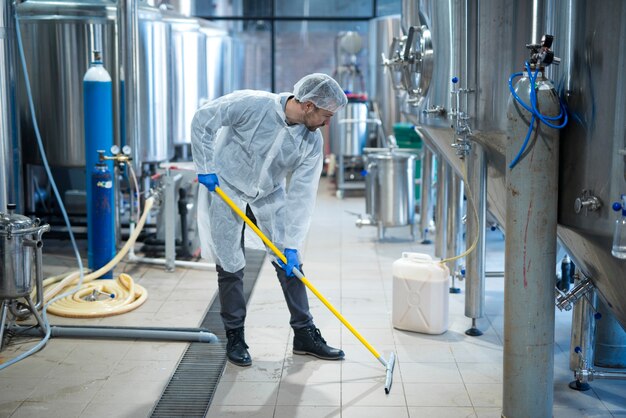 Professionele industriële reiniger in beschermende uniforme reinigingsvloer van voedselverwerkende fabriek