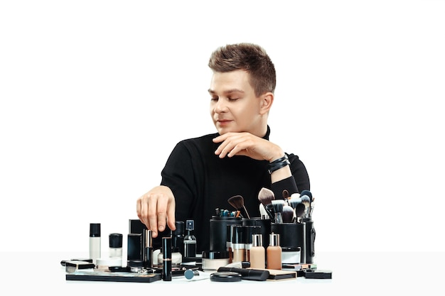Professionele make-up artist met tools geïsoleerd op witte studio achtergrond. De man in het vrouwelijk beroep. gendergelijkheid concept