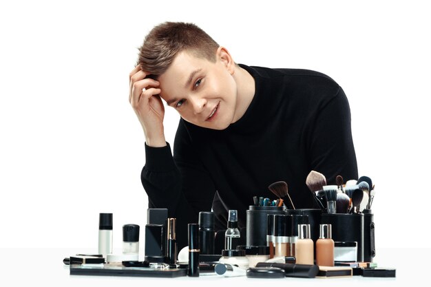 Professionele make-up artist met tools op wit wordt geïsoleerd. De man in vrouwelijk beroep. gendergelijkheid concept