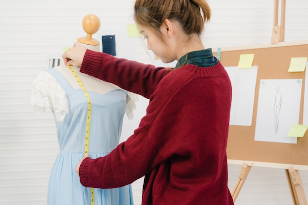 Professionele mooie Aziatische vrouwelijke modeontwerper werken meten jurk aan een mannequin kleding