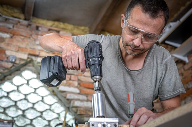 Professionele timmerman die met hout werkt en gereedschappen in huis bouwt.