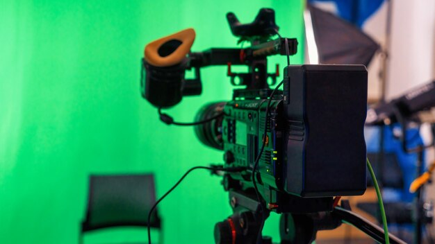 Professionele videocamera op een standaard met groene chromakey in een studio