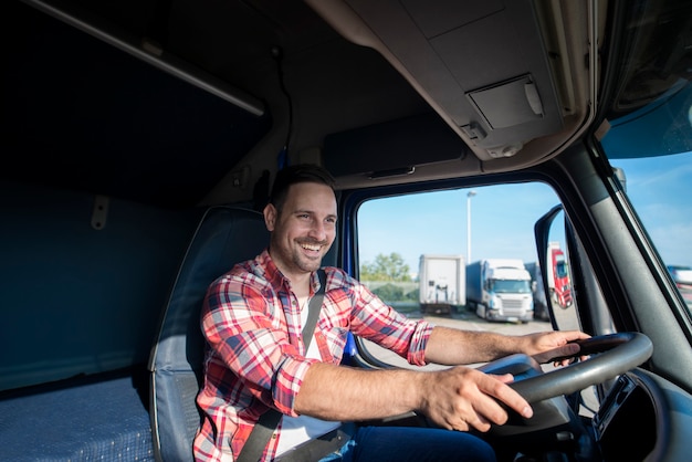 Professionele vrachtwagenchauffeur in vrijetijdskleding die veiligheidsgordel draagt en zijn vrachtwagen naar bestemming rijdt