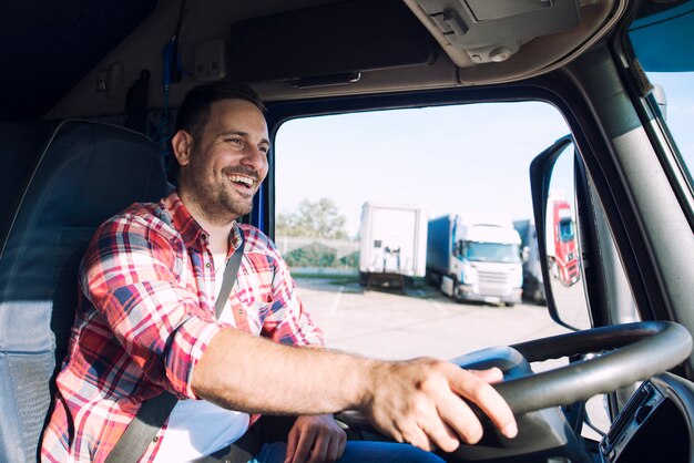 Professionele vrachtwagenchauffeur van middelbare leeftijd in vrijetijdskleding die vrachtwagenvoertuig bestuurt en vracht aflevert op de bestemming