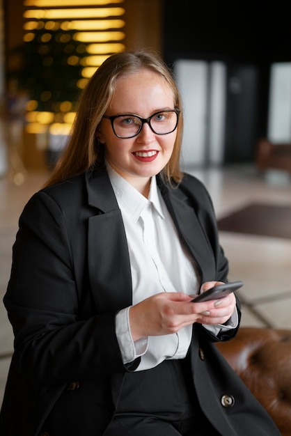 Professionele vrouw in stijlvol pak op kantoor met smartphone