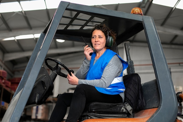 Professionele vrouwelijke chauffeur die een vorkheftruck bestuurt