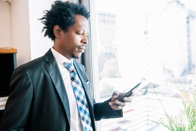 Professionele zakenman die zijn mobiele telefoon gebruikt terwijl hij op kantoor werkt