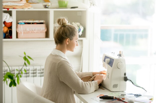 Profiel portret van een jonge aantrekkelijke vrouw bij naaimachine