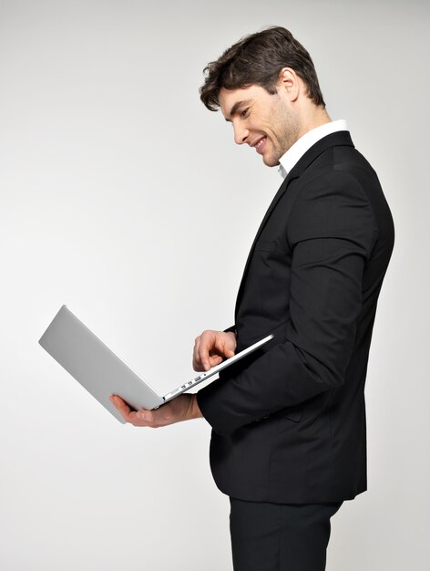 Profiel portret van lachende gelukkig zakenman met laptop in zwart pak.