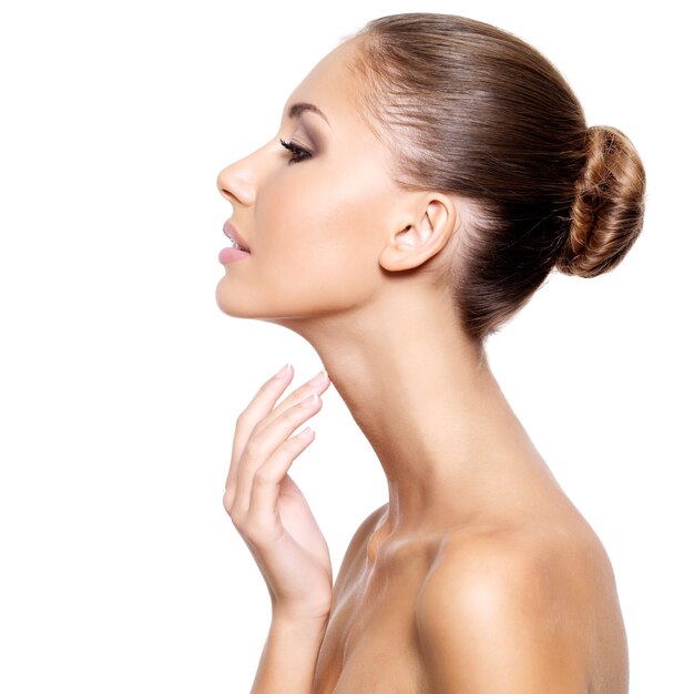 Profiel van een mooie jonge vrouw met frisse schone huid zachtjes aan te raken haar nek, geïsoleerd op wit