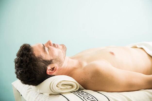 Profielweergave van een jonge man die op een bed ligt en een dutje doet na een massage in een spa