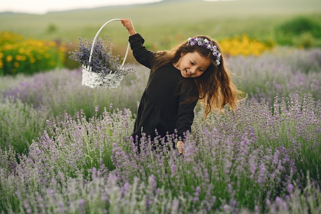 Provence kind ontspannen in lavendel veld. Kleine dame in een zwarte jurk. Meisje met tas.