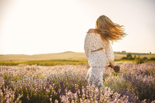 Provence vrouw ontspannen in lavendel veld. Dame in een witte jurk. Meisje met bloemenboeket.