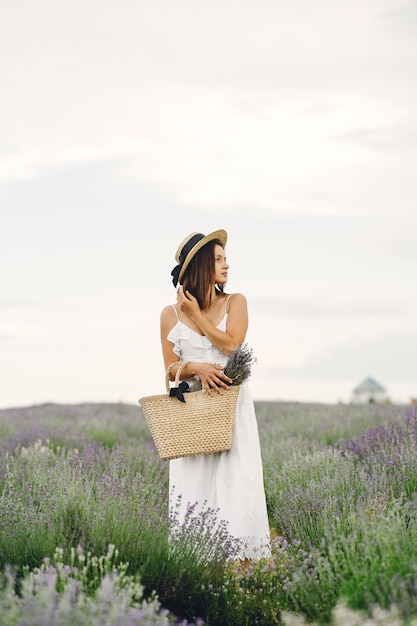 Gratis foto provence vrouw ontspannen in lavendel veld. dame in een witte jurk. meisje met tas.