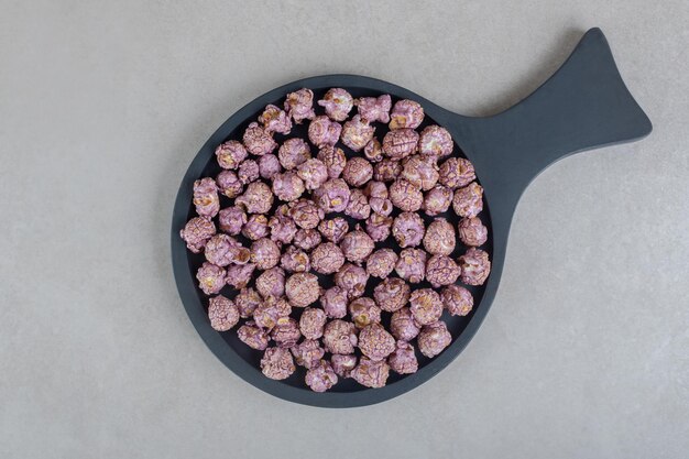 Purlple candy gecoate popcorn in een kleine pan op marmeren tafel.