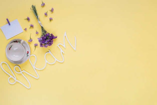 Purpere bloemen met droomwoord en lege kop op gele oppervlakte