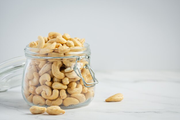 Rauwe cashewnoten in een open glazen pot op marmeren achtergrond