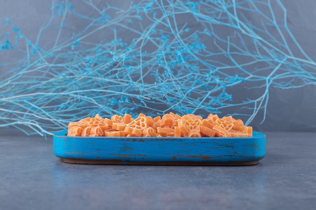 Gratis foto rauwe hartvormige pasta op blauw bord.