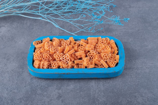 Gratis foto rauwe hartvormige pasta op blauw bord.