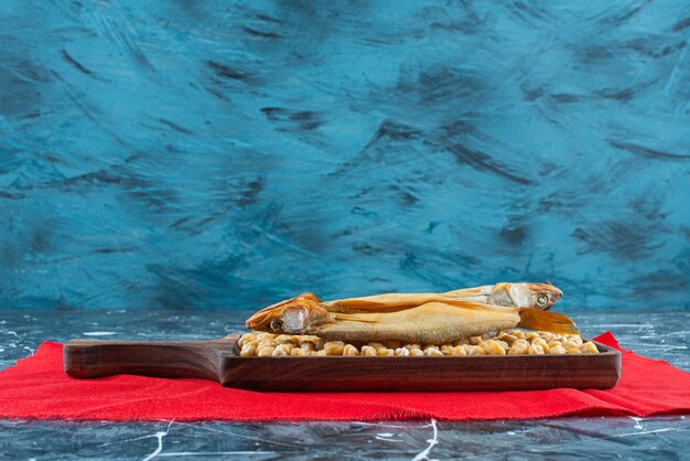 Rauwe kip erwt en geroosterde vis op een bord op rode textuur, op de blauwe tafel.