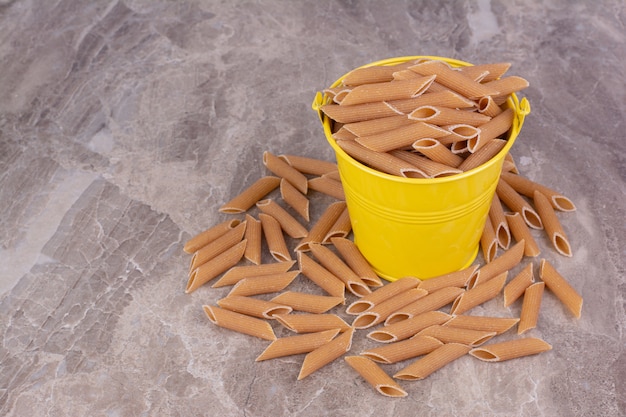 Gratis foto rauwe pasta's in een metallic gele container.