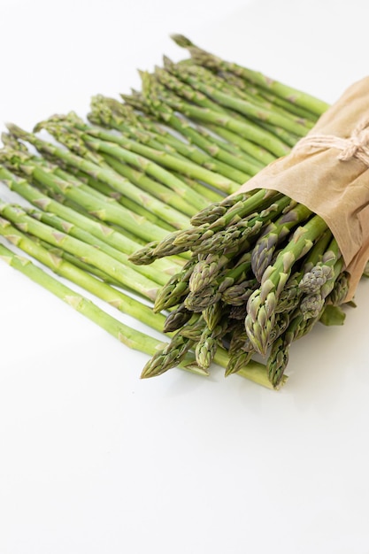 Rauwe stengels asperges vastgebonden met touw Plantaardig voedsel geïsoleerd op een witte achtergrond