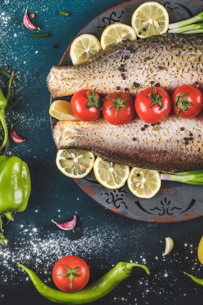 Gratis foto rauwe zeevruchten met tomaten en citroen op de blauwe tafel