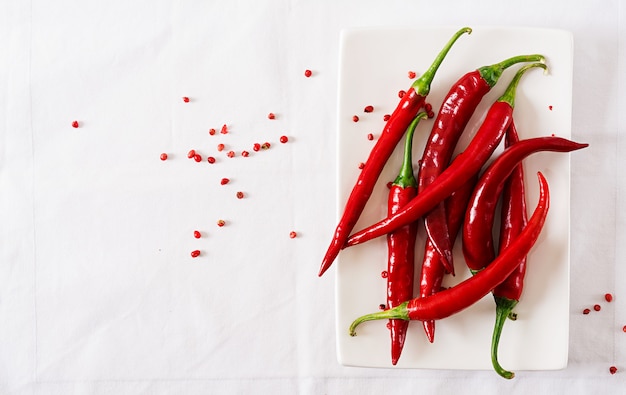 Red hot chili peppers in plaat op witte tafel. Bovenaanzicht. Plat liggen
